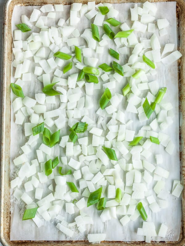 a baking sheet with chopped frozen onions on a piece of parchment