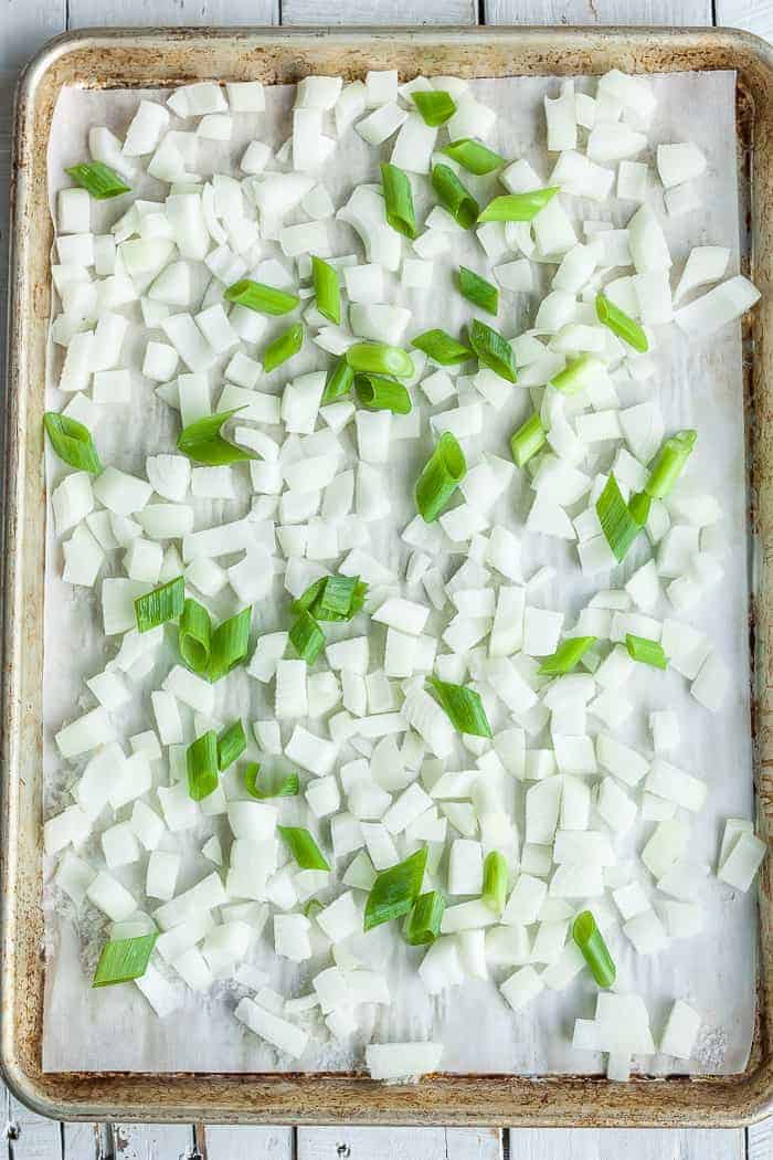 a baking sheet with chopped frozen onions on a piece of parchment
