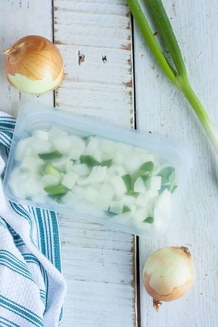 chopped frozen onions in a reusable freezer bag with whole and green onions