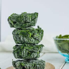 four cubes of frozen spinach stacked on top of a muffin liner