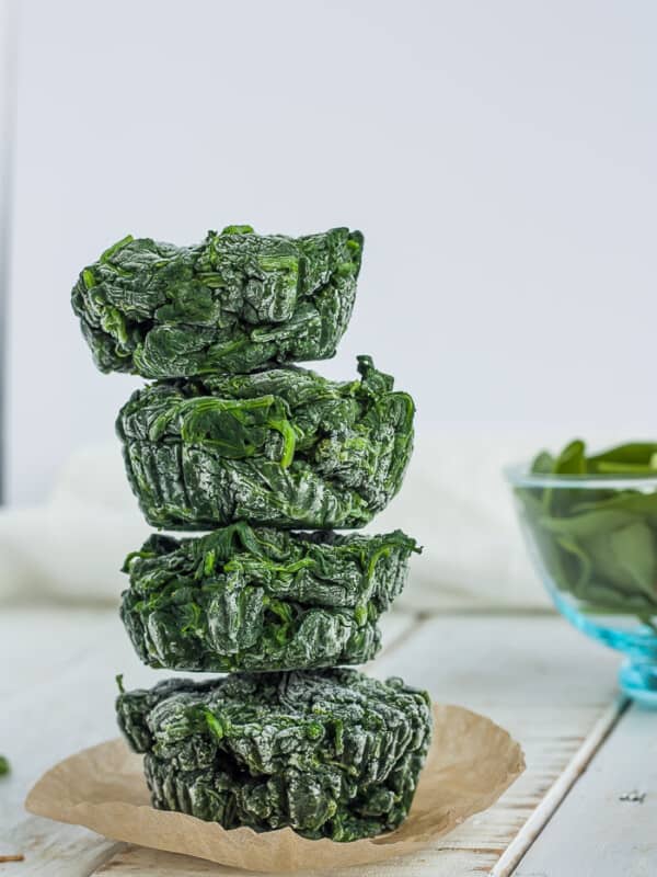 four cubes of frozen spinach stacked on top of a muffin liner