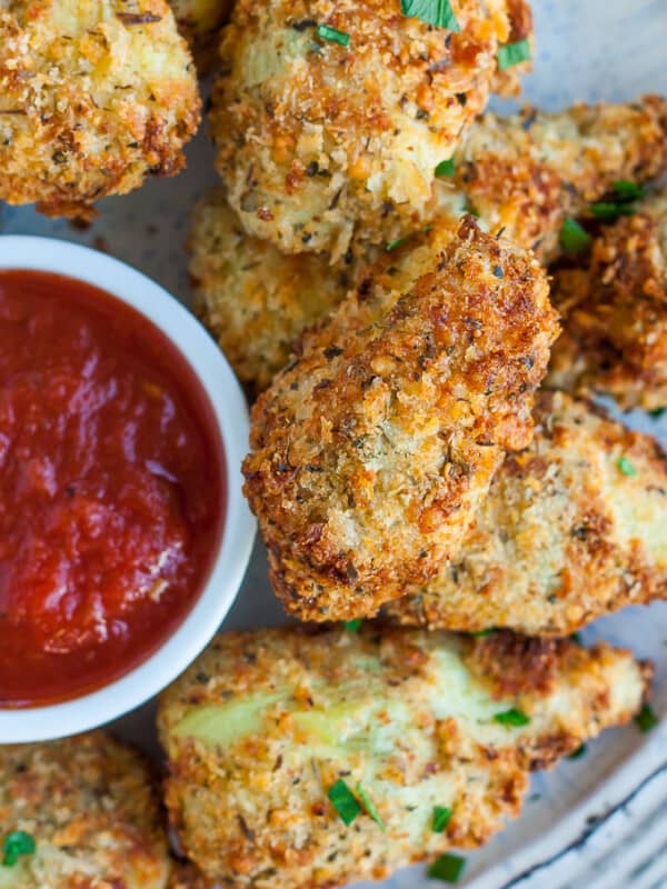 Fried artichoke hearts on a plate with a small bowl of marinara