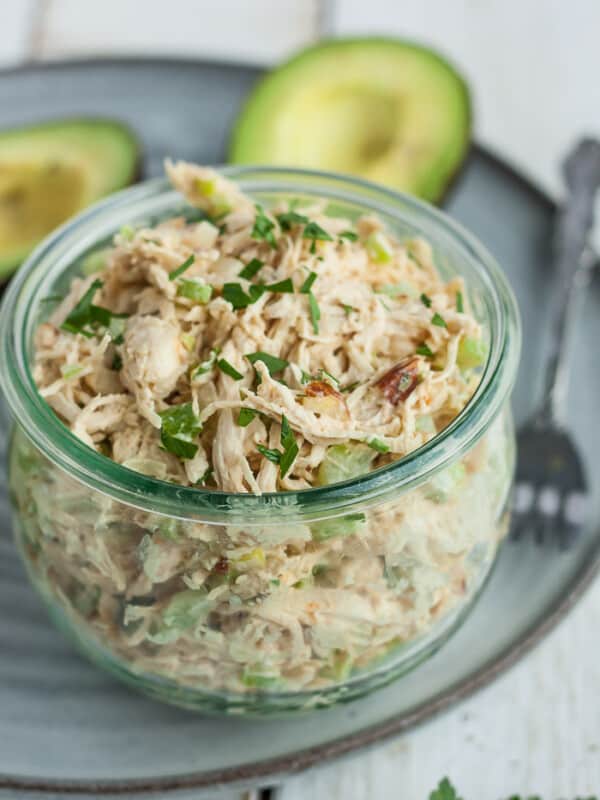 A glass bowl of whole30 chicken salad with avocado on a grey plate
