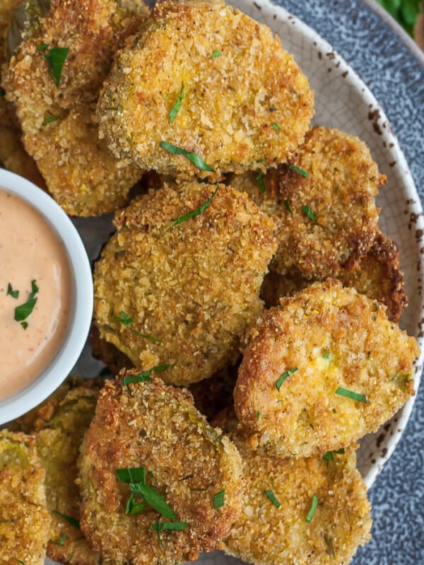 a grey plate with homemade fried pickles topped with chopped parsley