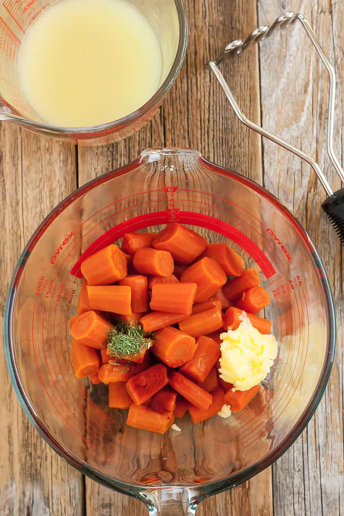 a bowl of cubed cooked carrots topped with dill and ghee.