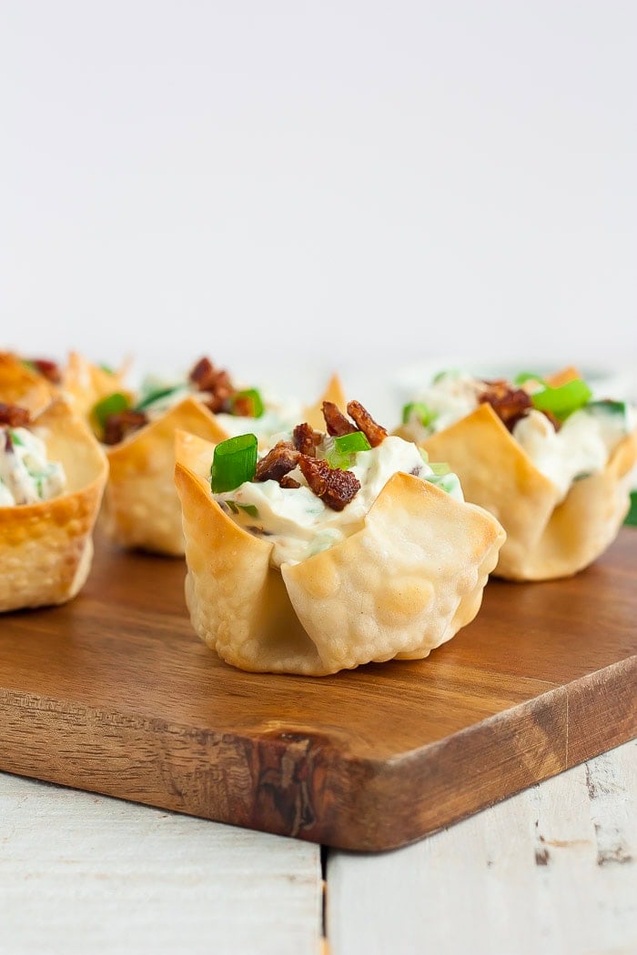 a side profile of jalapeño popper wonton bites on a wooden board.