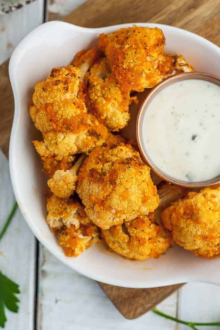 A bowl of buffalo cauliflower with a dish of ranch dressing