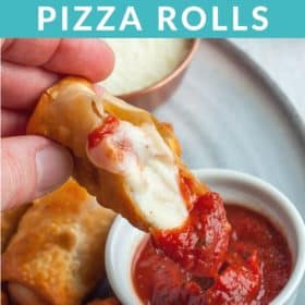 A hand dipping a pizza roll into a bowl of sauce