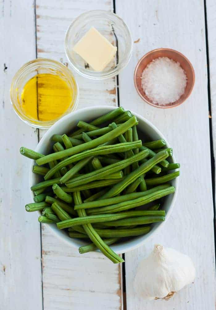 A bowl of green beans, olive oil, butter, salt, and garlic