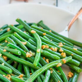 a bowl of garlic butter green beans with a fork.