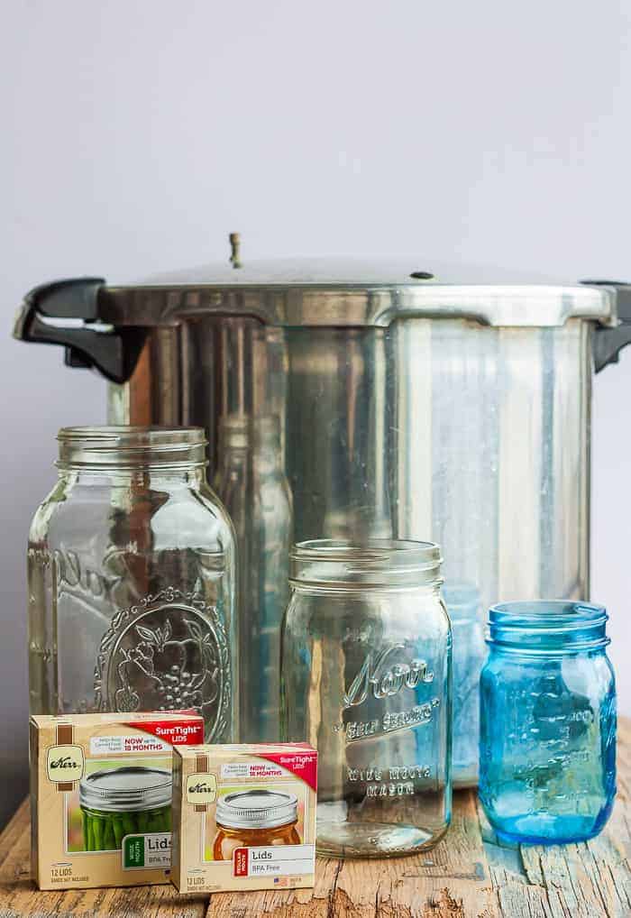 a pressure canner with some jars, and 2 boxes of canning lids on a wooden board