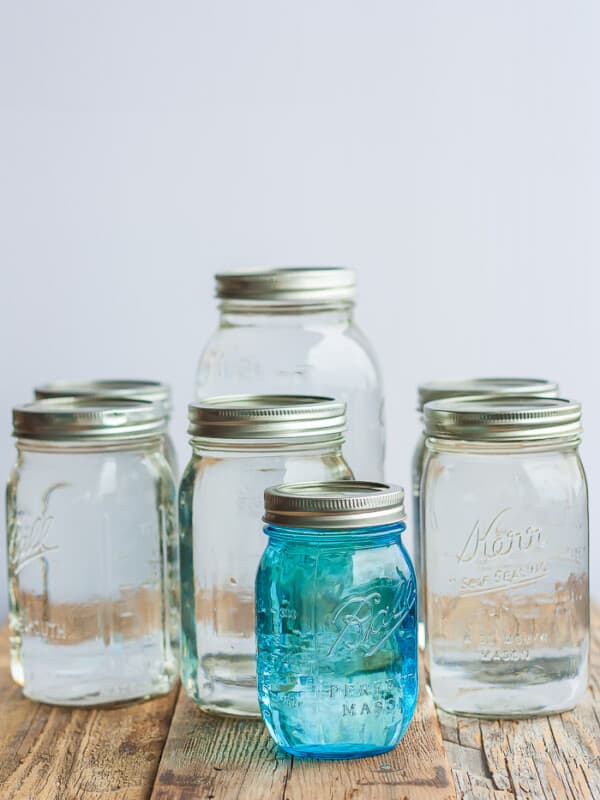Canning jars of different sizes full of canned water on a wooden board
