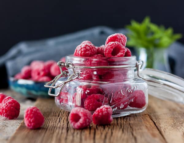 a jar of frozen raspberries with a sprig of mint