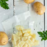 a bag of diced potatoes on a white board with whole potatoes and parsley