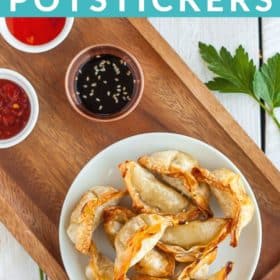 A white plate with crispy air fryer potstickers and a small bowl of dipping sauce