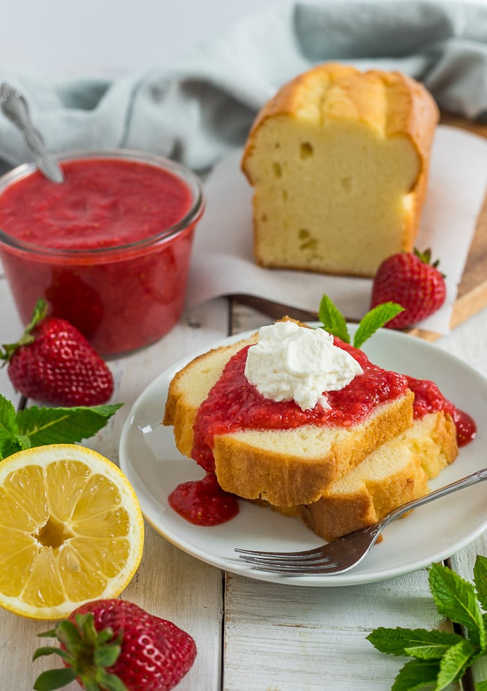pound cake on a dish topped with homemade strawberry puree and whipped cream