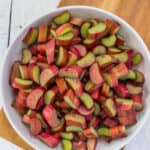 a white bowl with chopped rhubarb on a cutting board