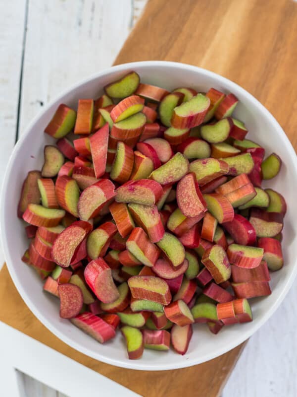 a white bowl with chopped rhubarb on a cutting board