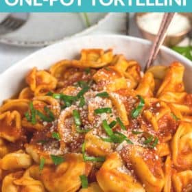a white bowl of tortellini topped with chopped basil