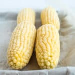 4 frozen ears of corn on a baking sheet