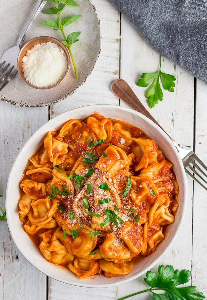 a bowl of pasta with marinara and a bowl of shredded Parm.