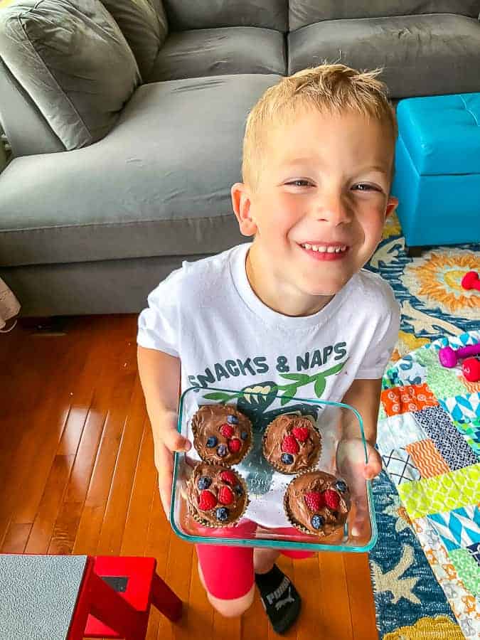 a boy holding cupcakes
