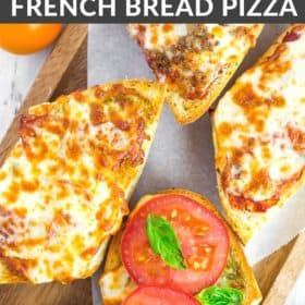 french bread pizzas on a wooden tray with tomatoes and other toppings on a white board