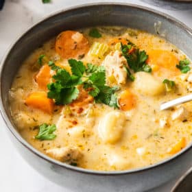 a grey bowl of Instant Pot chicken gnocchi soup with a spoon