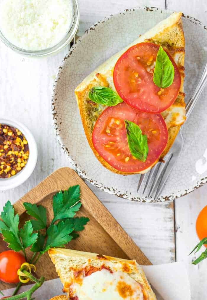 a piece of air fryer french bread pizza topped with fresh tomatoes and basil
