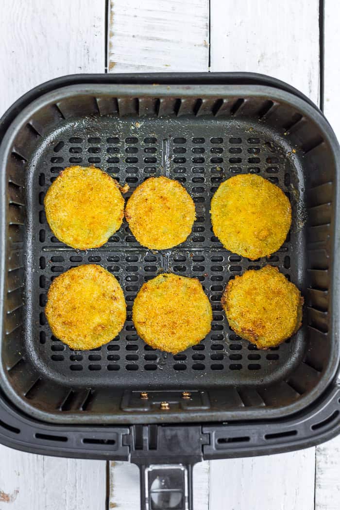breaded tomatoes sitting in an air fryer.