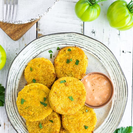 a plate of fried green tomatoes on a white board with small green tomatoes