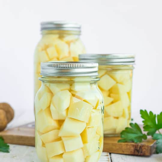 3 jars of canned potatoes on a wooden board