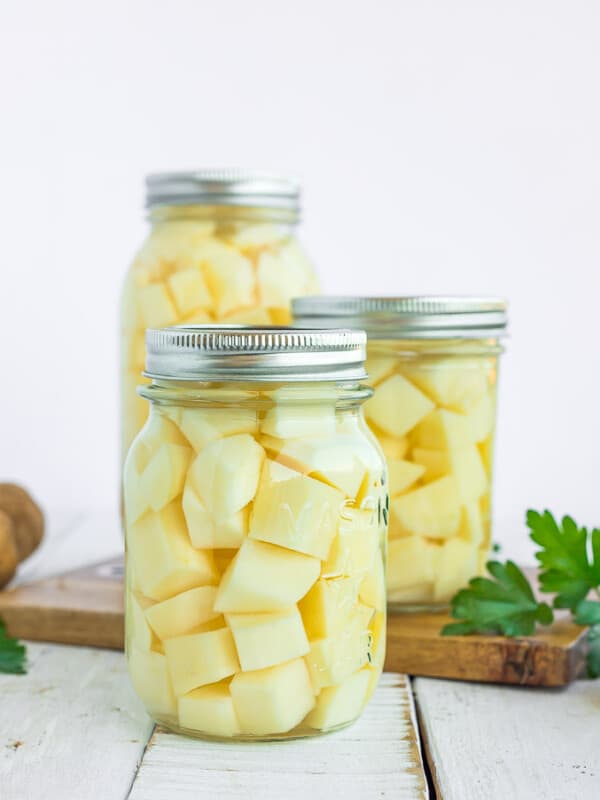 3 jars of canned potatoes on a wooden board