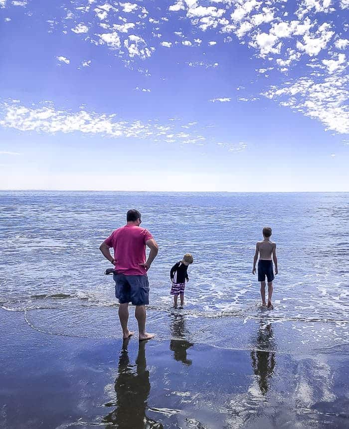 2 boys and a dad standing in the ocean