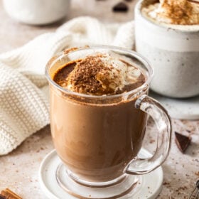 a glass mug of hot chocolate topped with whipped cream.