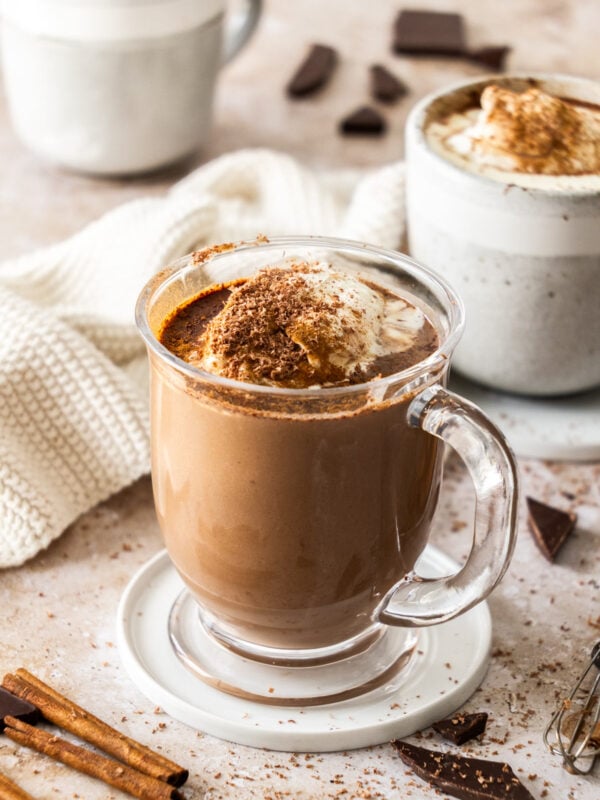 a glass mug of hot chocolate topped with whipped cream.