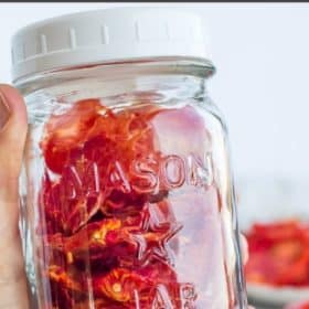 a hand holding a jar of dried tomatoes