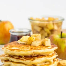 a stack of apple pancakes topped with sliced cinnamon apples.