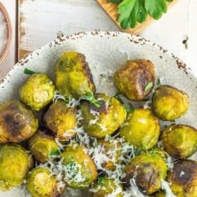 a grey plate with roasted frozen brussel sprouts topped with minced parsley