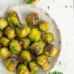 a grey plate with roasted frozen brussel sprouts topped with minced parsley