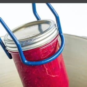 Canning tongs with a jar of cranberry sauce in a canner