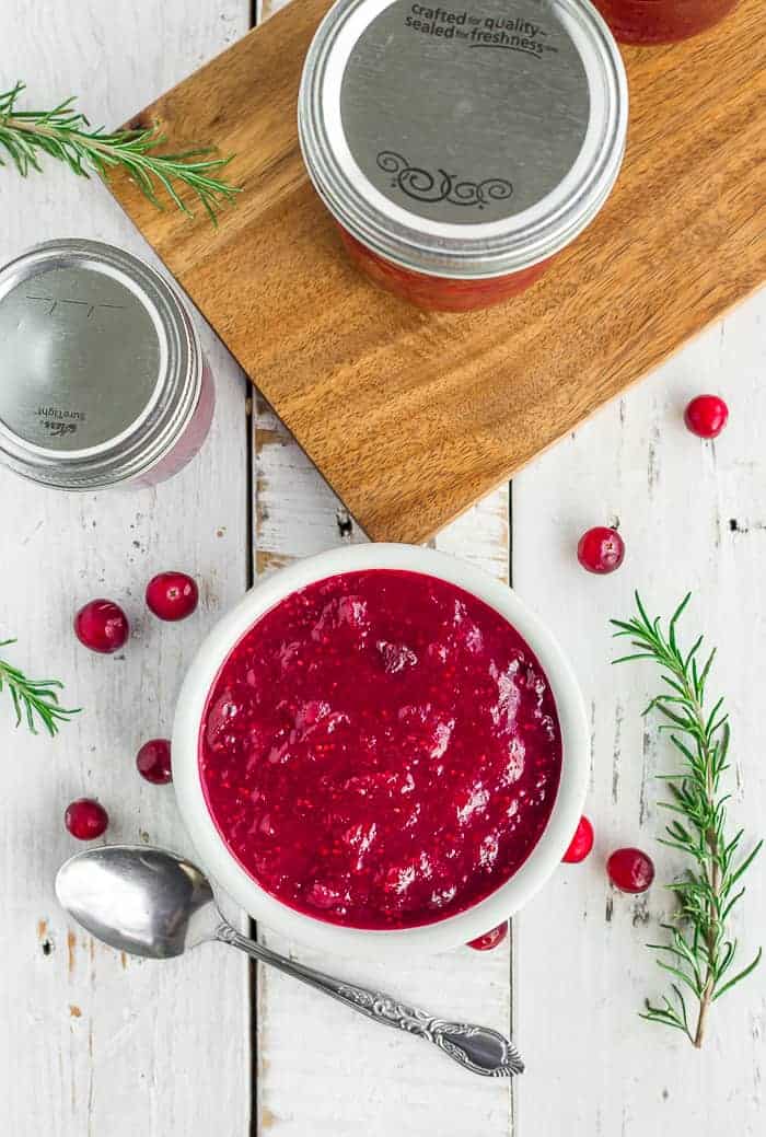 a bowl from canning cranberry sauce surrounded by jars of canned cranberry relish