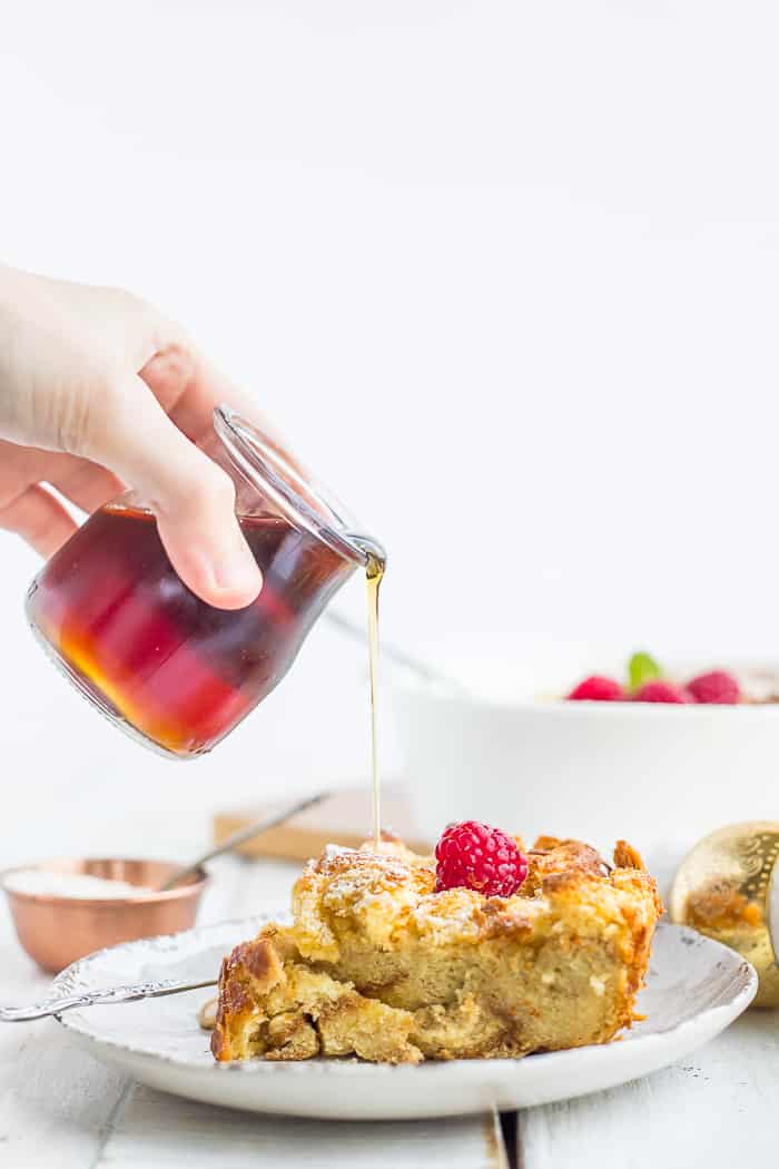 maple syrup being poured over a plate of bread pudding