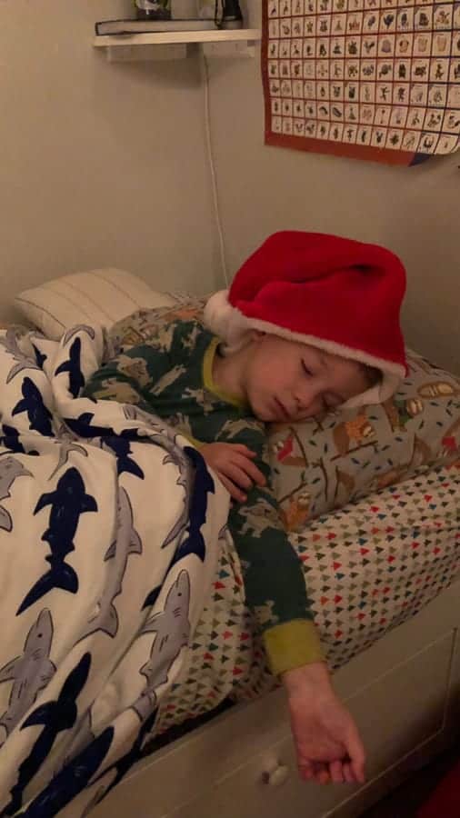 a little kid sleeping with a santa hat on