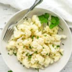 a white bowl of instant pot cauilflower topped with parsley