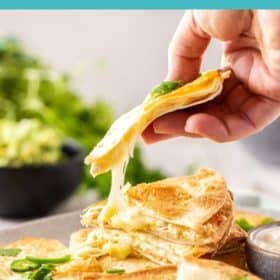 A hand holding a quesadilla with cheese being pulled