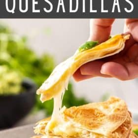 A hand holding a quesadilla with cheese being pulled