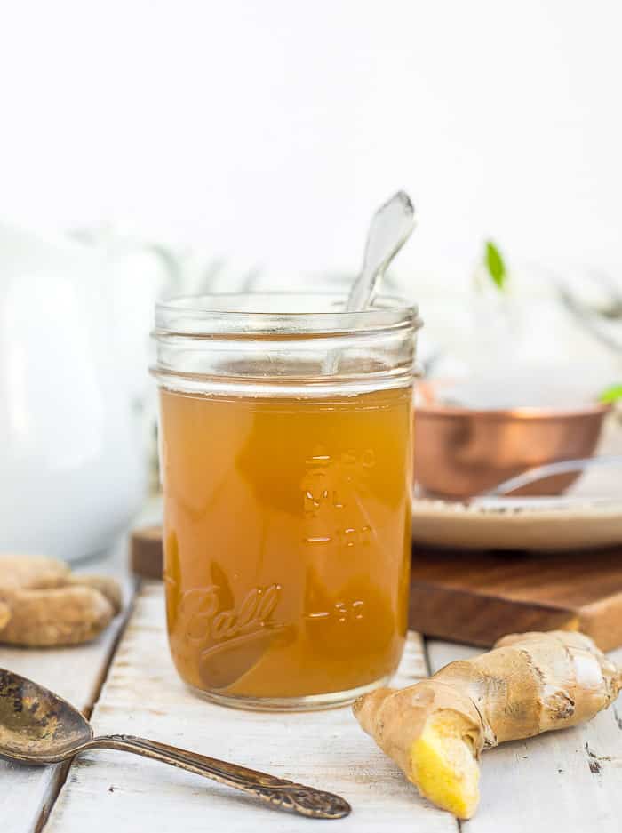 a jar of honey ginger syrup with a spoon 