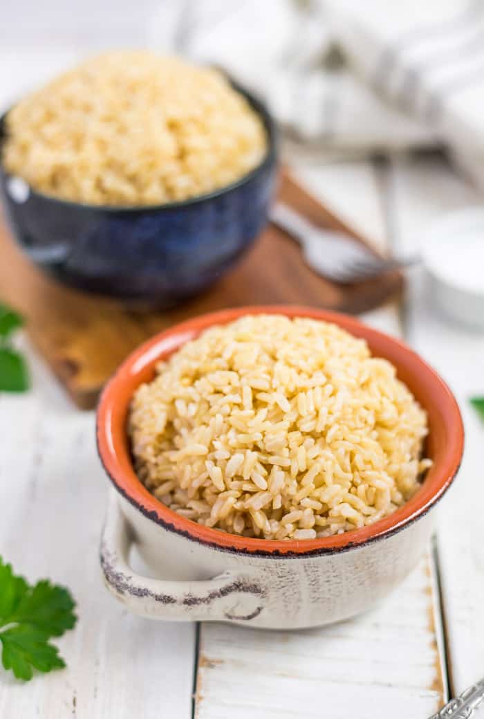 Make perfect Instant Pot Brown Jasmine Rice for a speedy side dish that the whole family will love! Made in a flash in a pressure cooker, this healthy rice is great for meal prep and is pairs well with so many dishes. No pressure cooker? You’ll also find stovetop instructions in the recipe. Two bowls of Instant Pot brown rice on a white board