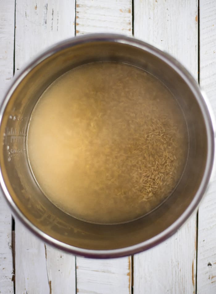 uncooked brown rice and water in a pressure cooker.